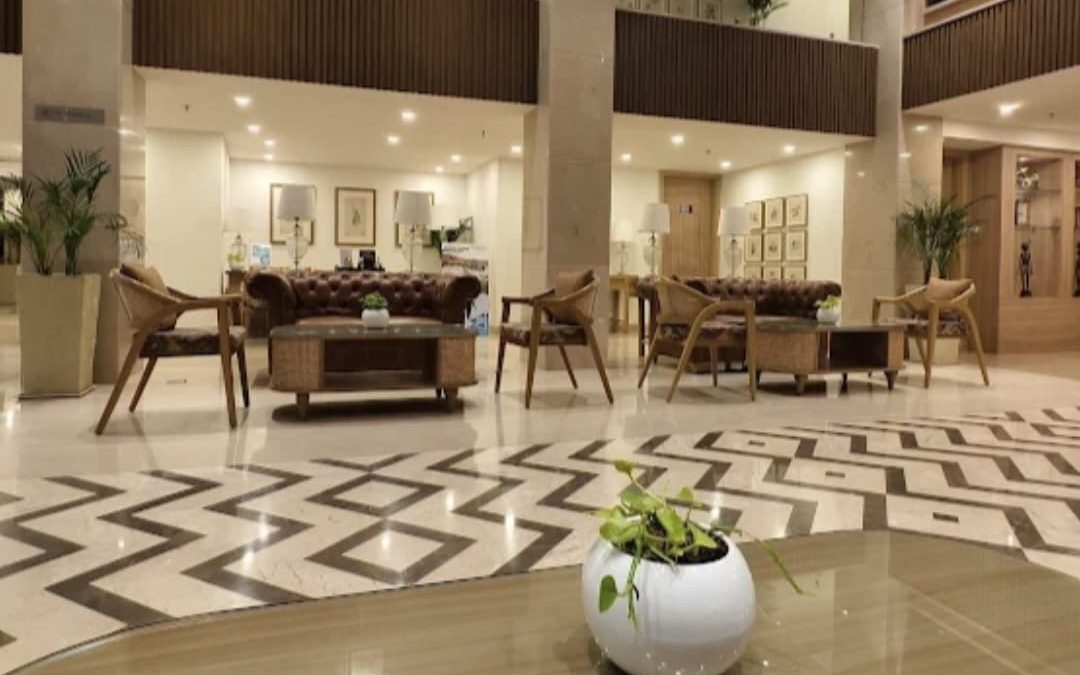 Double-height entrance hall with a round centre table, lounge seating and a patterned marble floor
