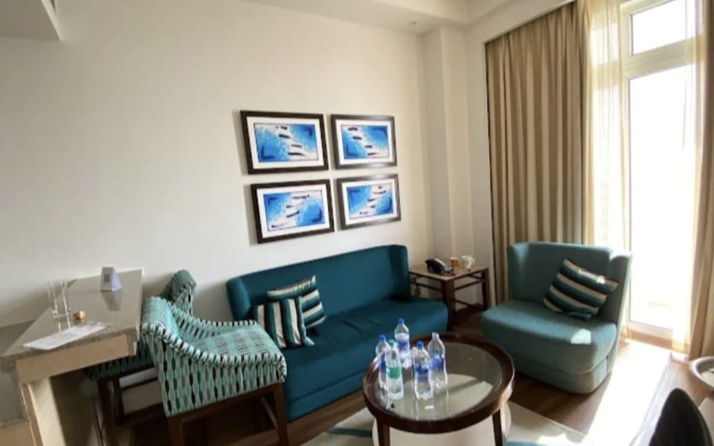 Guest room with a teal sofa, armchairs and a round coffee table in a Dubai apartment