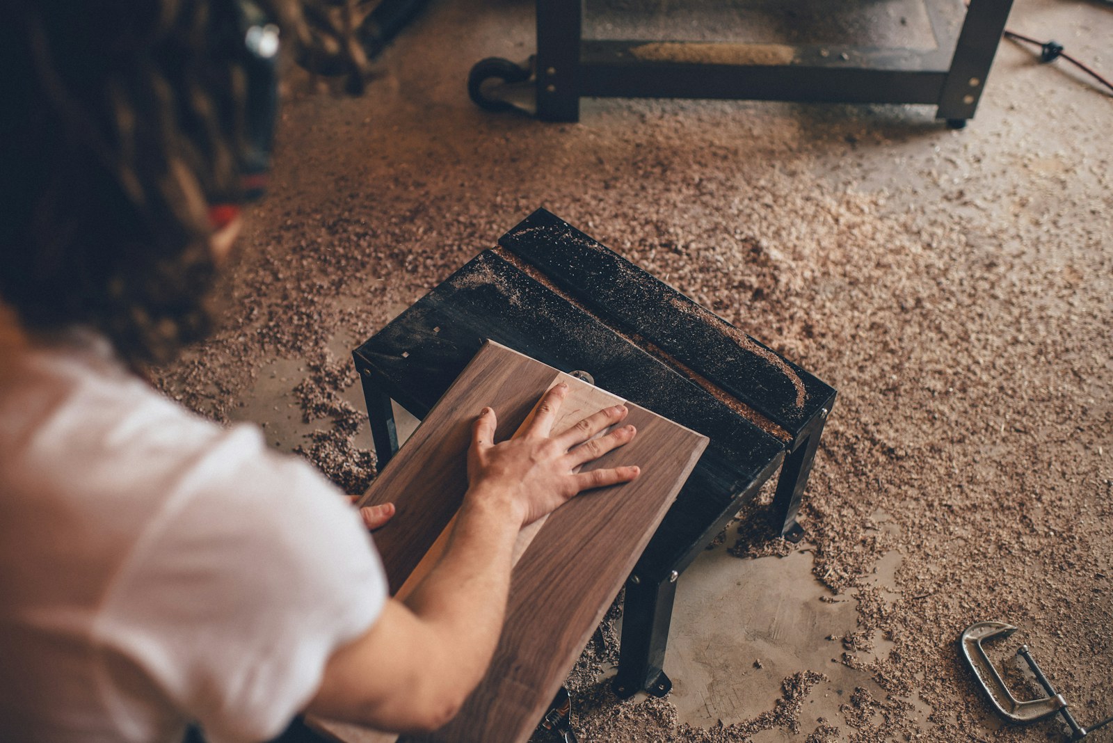 Craftsman's hand on a planed hardwood board in a furniture workshop