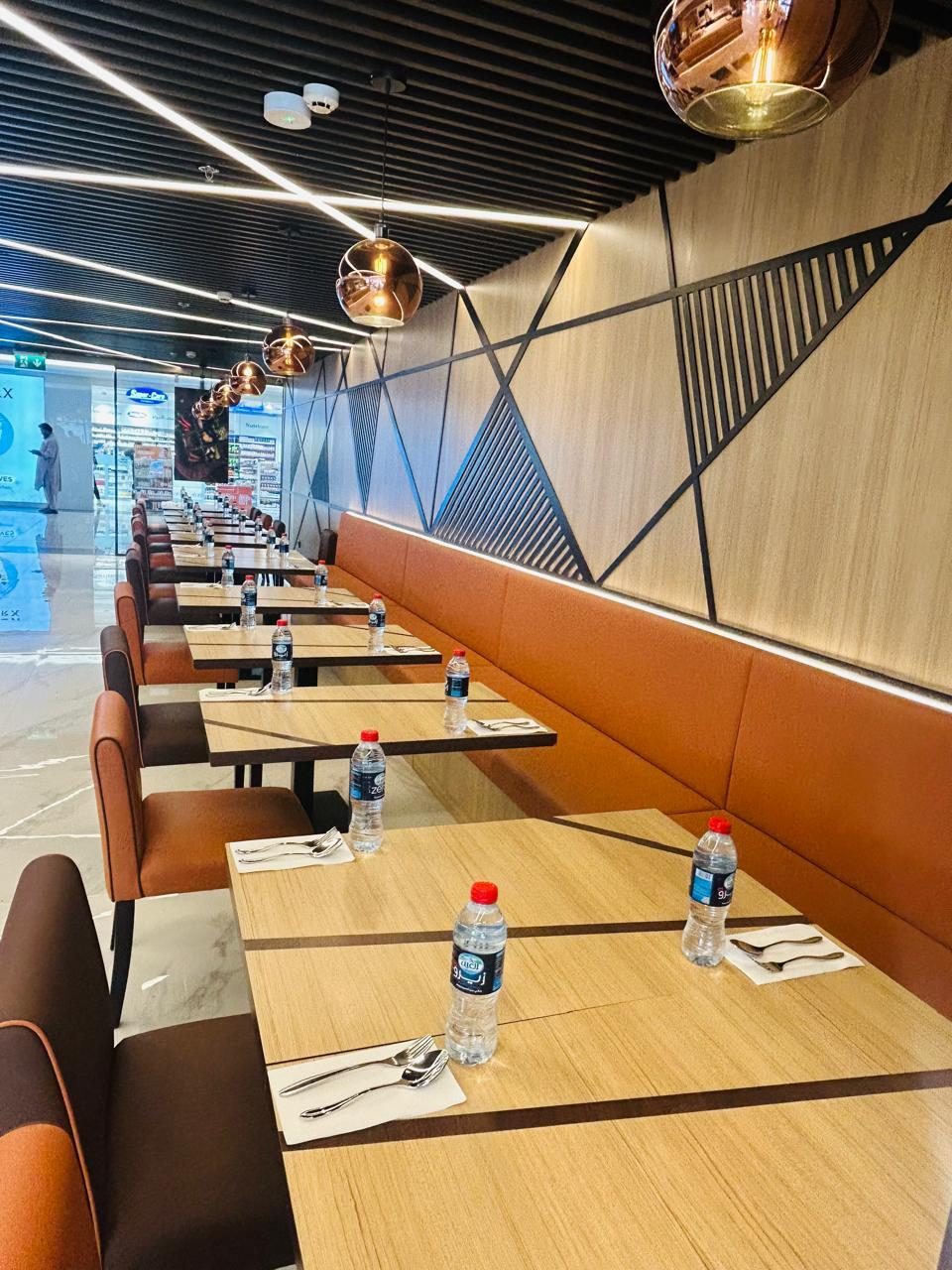 Long restaurant banquette in orange leather with a timber-framed back and a row of dining tables