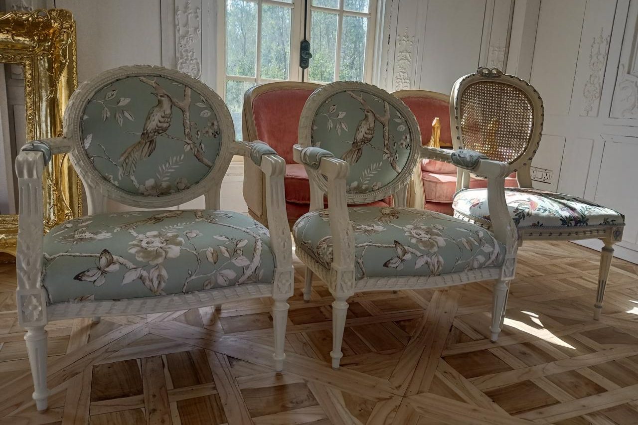 Louis XVI style fauteuils with oval medallion backs, ivory painted frames and a bird-print fabric