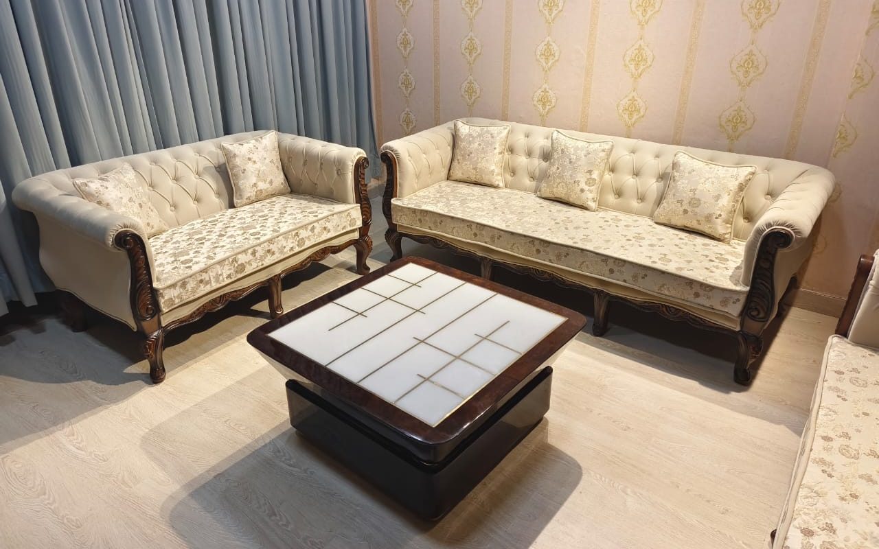 Square coffee table with a tiled top in front of a classic tufted sofa set in a Dubai living room