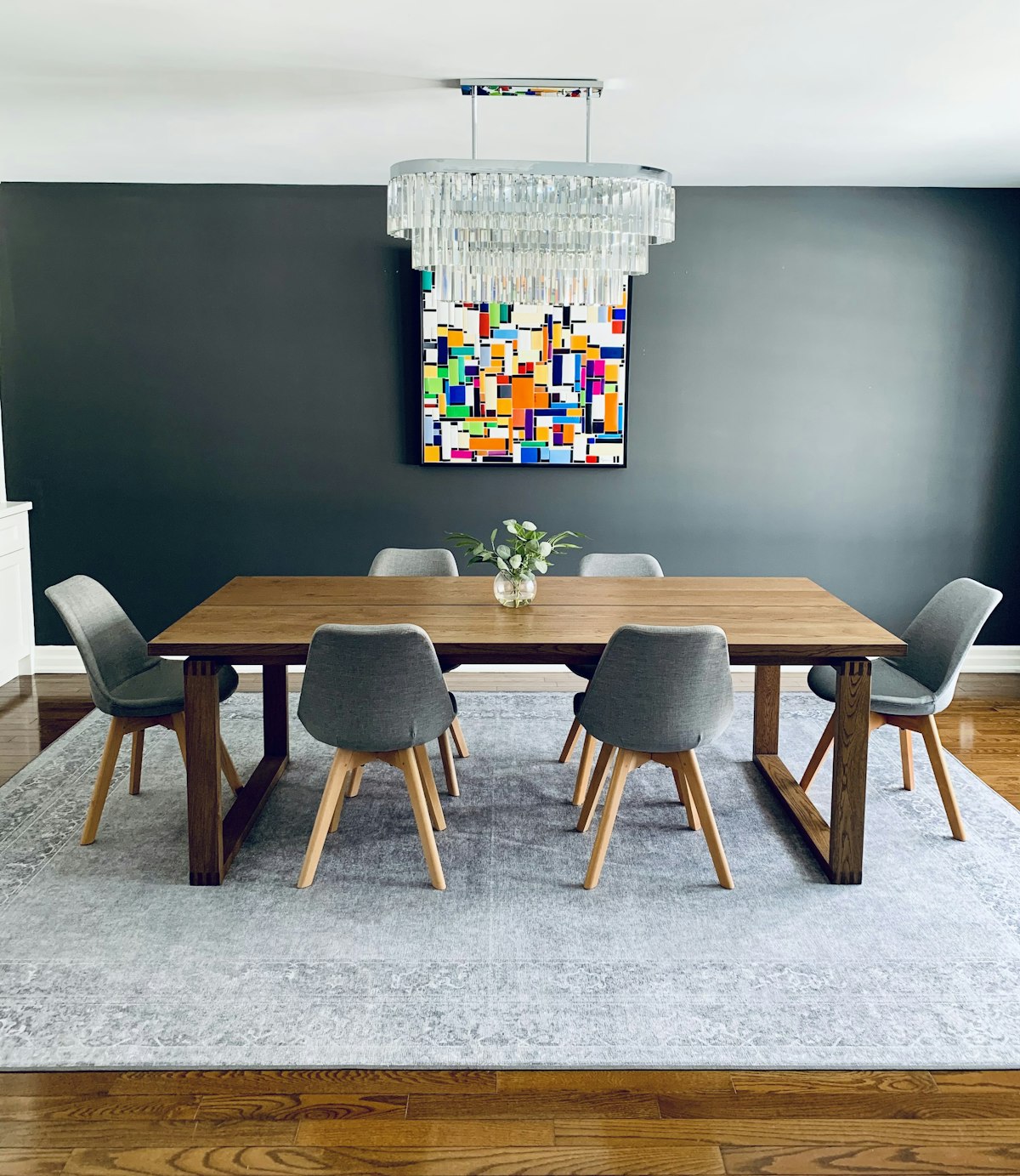 Contemporary wooden dining table with crystal chandelier and upholstered chairs